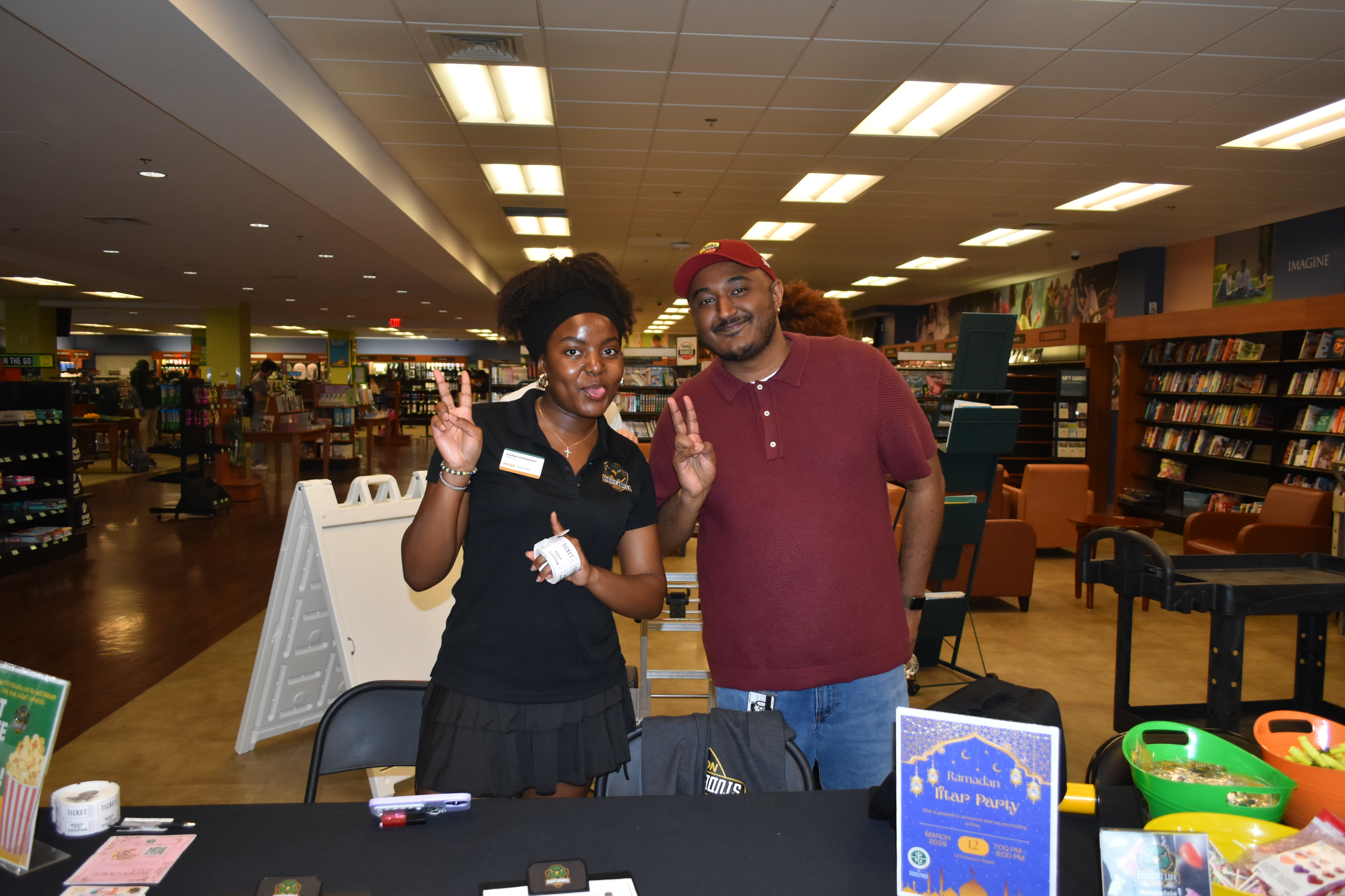 Two student life representatives taking a photo by a table with goodies and brochures