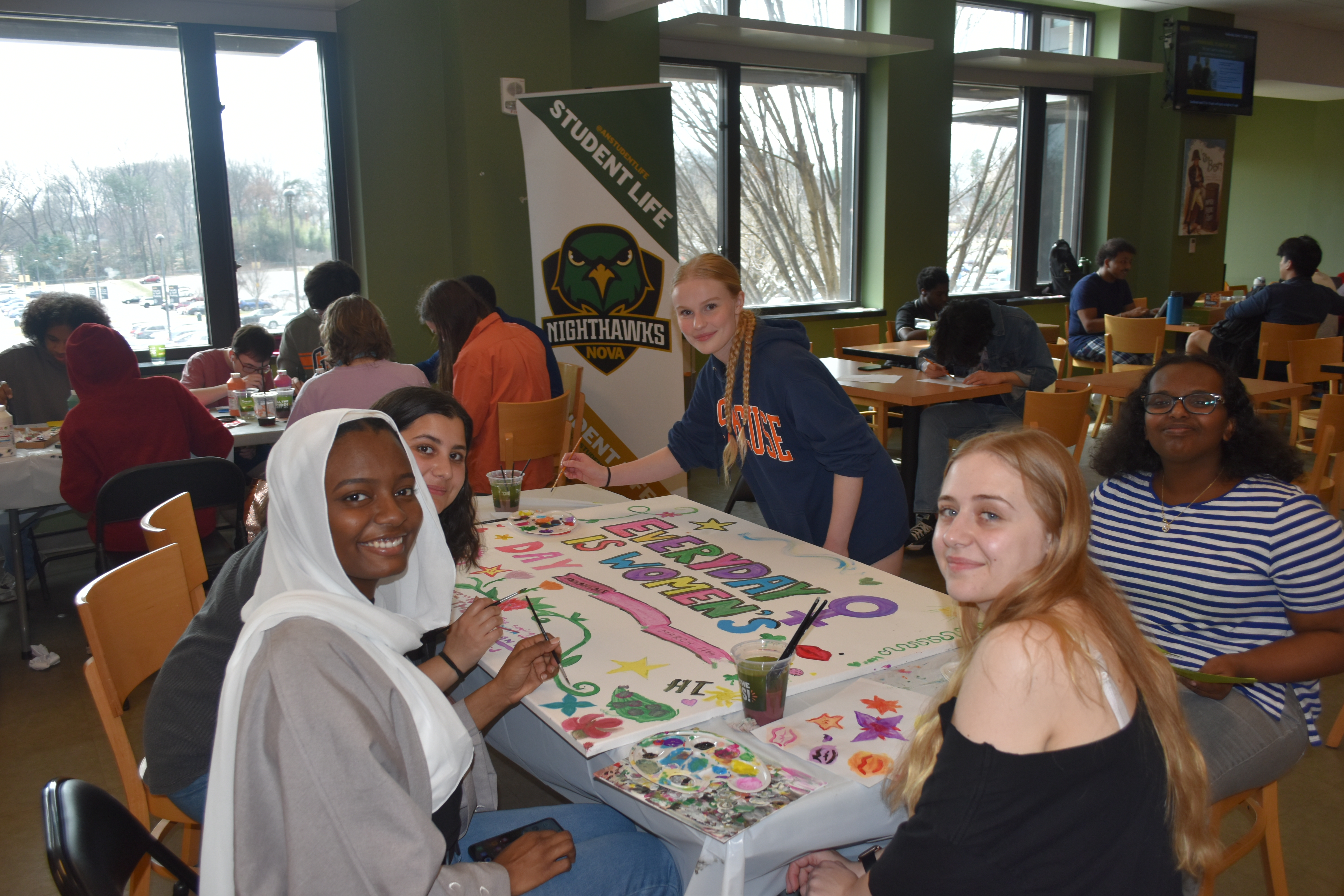 Students posing for a photo while seated at a table for group painting actvity