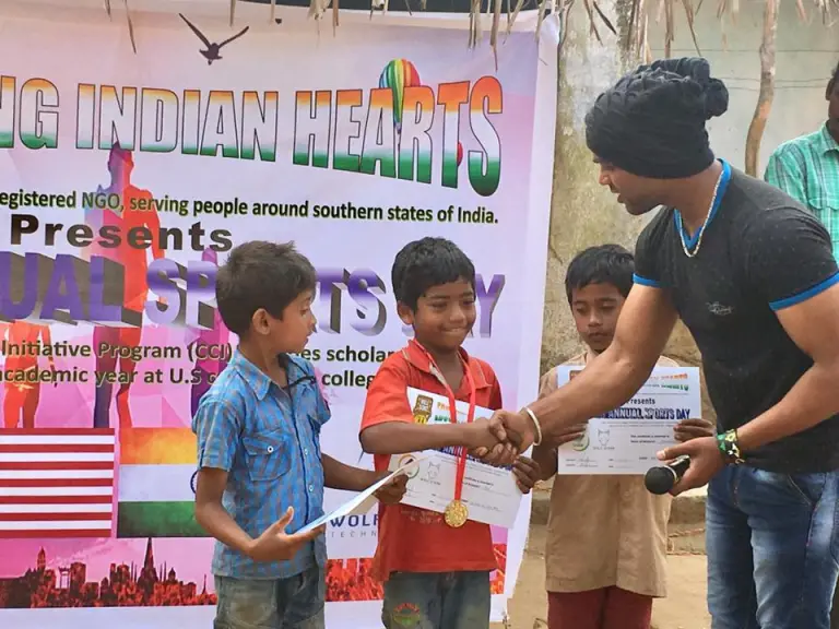 CCI alumnus Rajesh (right) passes out certificates to children during his organization’s “Sports Day” event.