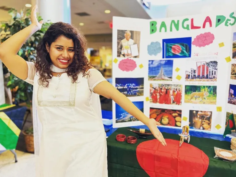 CCI participant Tanzila Prarona of Bangladesh stands proudly in front of the country booth she presents during International Education Week 2021.