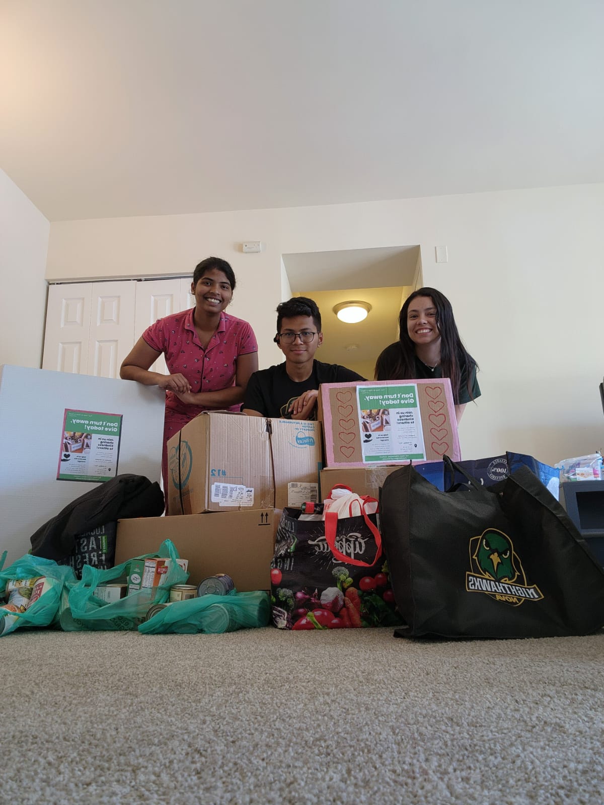 Three students with donation boxes for CIP