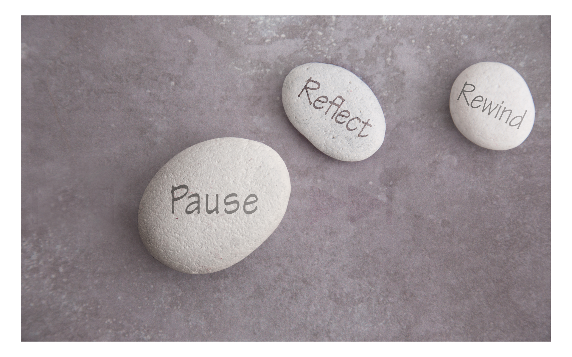 Three stones that have pause, reflect, and rewind engraved on them. 