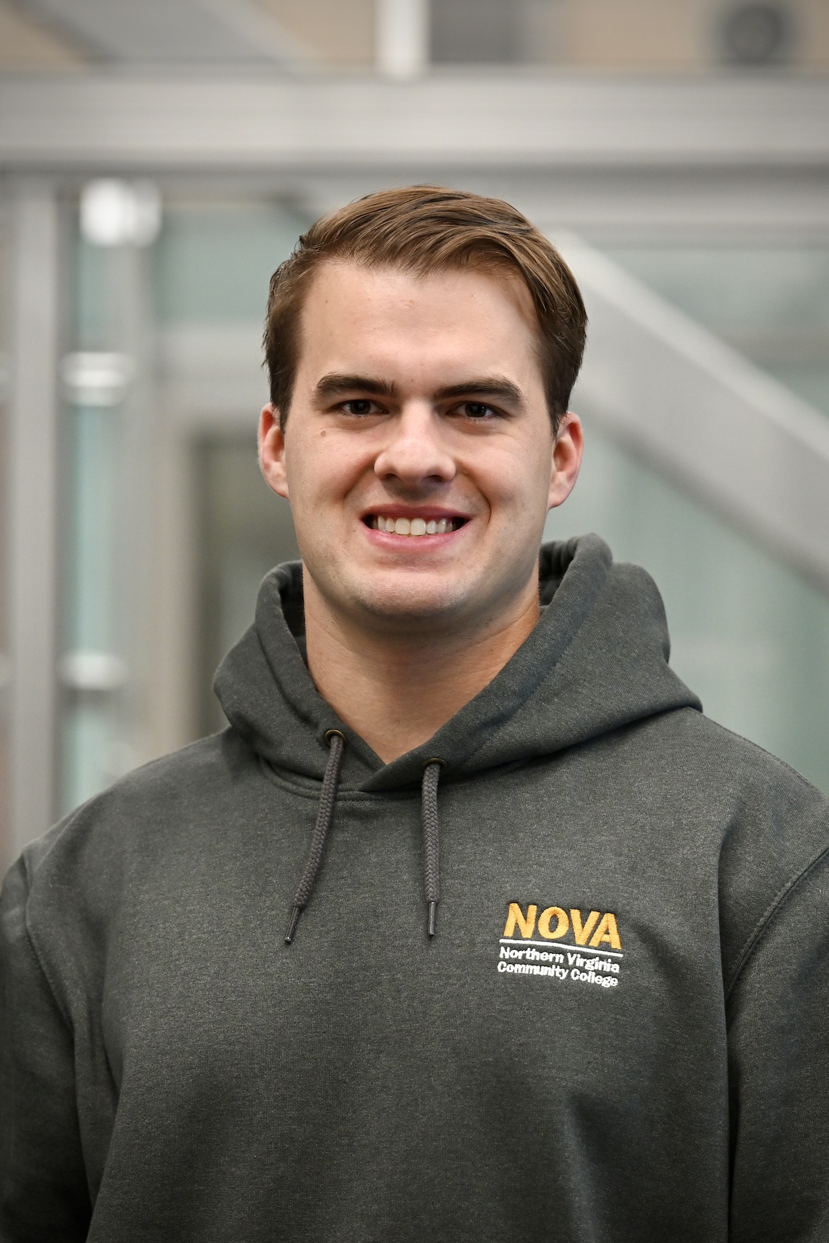 A portrait of Kody Karman smiling at the camera wearing a NOVA hoodie in the data center training facility.
